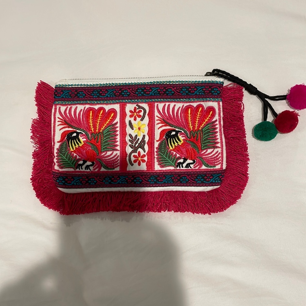 Embroidered clutch with magenta, fringe, and tassel detail with small pom-poms.